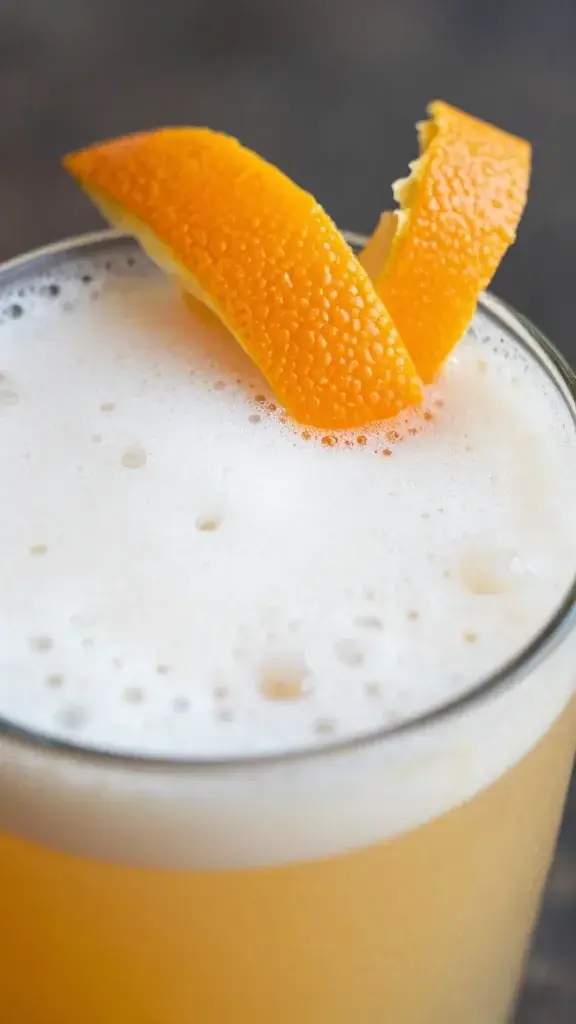 Close-up of orange peel garnish over Mai Tai foam