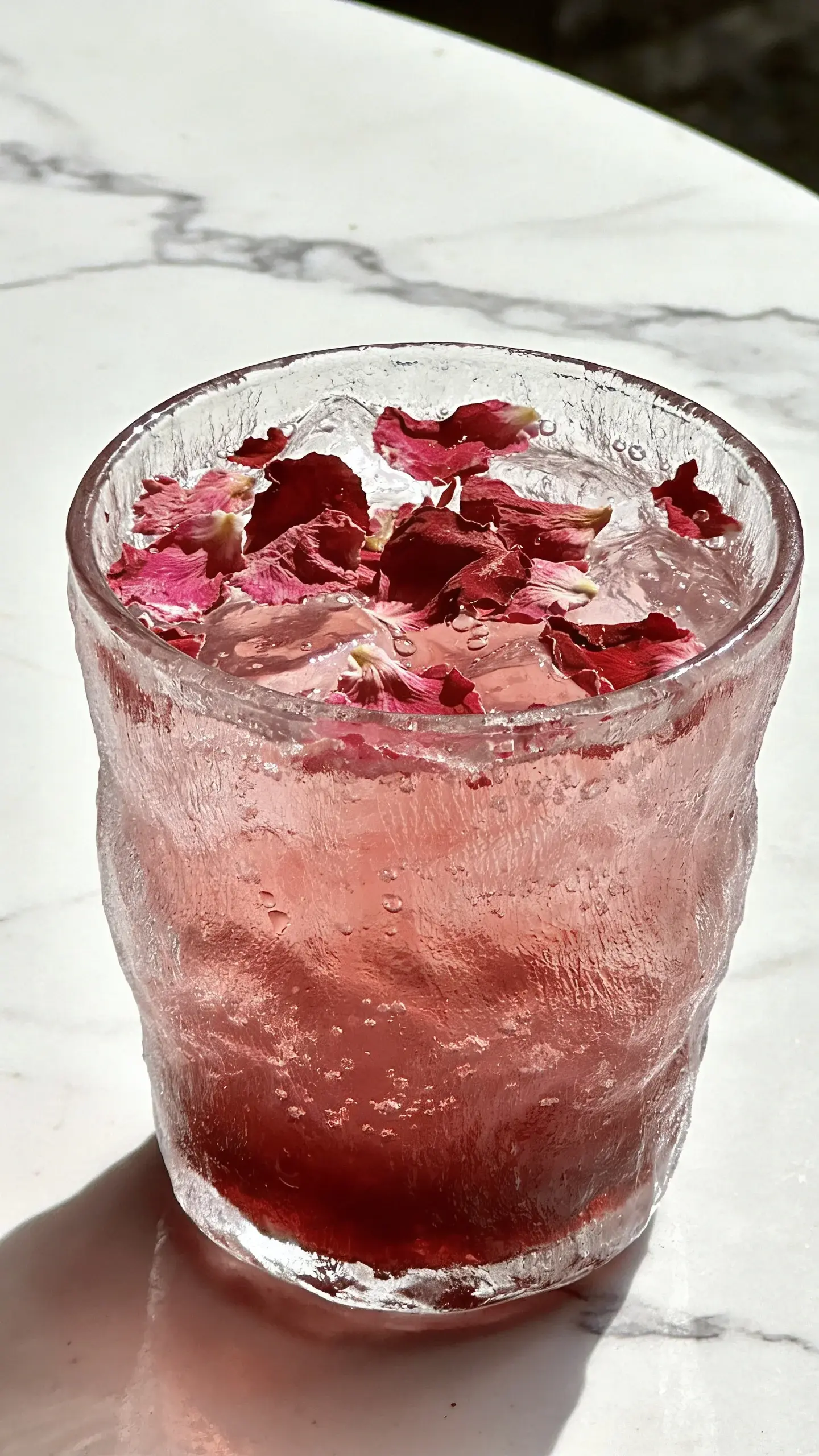 Hibiscus rose mocktail in frosted glass on white marble